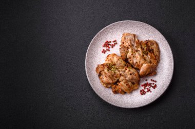 Koyu beton bir arka planda tuzlu, baharatlı ve otlu ızgara kemiksiz tavuk budu.