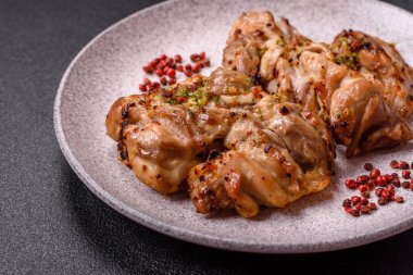 Koyu beton bir arka planda tuzlu, baharatlı ve otlu ızgara kemiksiz tavuk budu.