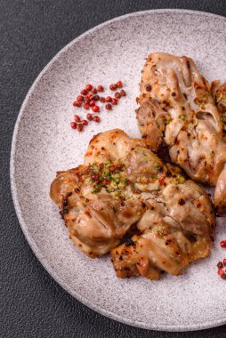 Koyu beton bir arka planda tuzlu, baharatlı ve otlu ızgara kemiksiz tavuk budu.