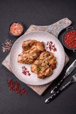 Koyu beton bir arka planda tuzlu, baharatlı ve otlu ızgara kemiksiz tavuk budu.