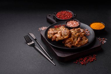 Koyu beton bir arka planda tuzlu, baharatlı ve otlu ızgara kemiksiz tavuk budu.