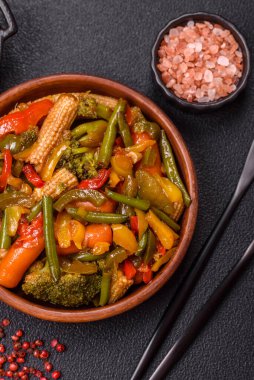 Sebze karışımı mısır, havuç, biber, brokoli, teriyaki soslu soğan koyu beton arka planda seramik bir tabakta