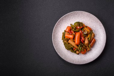 Sebze karışımı mısır, havuç, biber, brokoli, teriyaki soslu soğan koyu beton arka planda seramik bir tabakta