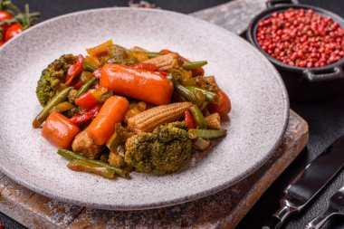 Sebze karışımı mısır, havuç, biber, brokoli, teriyaki soslu soğan koyu beton arka planda seramik bir tabakta