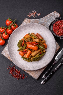 Sebze karışımı mısır, havuç, biber, brokoli, teriyaki soslu soğan koyu beton arka planda seramik bir tabakta