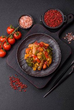 Sebze karışımı mısır, havuç, biber, brokoli, teriyaki soslu soğan koyu beton arka planda seramik bir tabakta