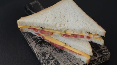 Jambonlu, salamlı, domatesli, hardallı, tuzlu ve baharatlı sandviç.