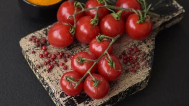 Koyu beton arka planda tuzlu ve baharatlı olgun kırmızı kiraz domatesleri.