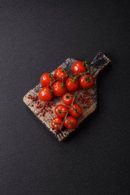 Koyu beton arka planda tuzlu ve baharatlı olgun kırmızı kiraz domatesleri.