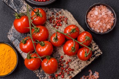 Koyu beton arka planda tuzlu ve baharatlı olgun kırmızı kiraz domatesleri.