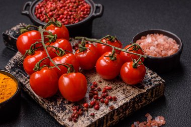 Koyu beton arka planda tuzlu ve baharatlı olgun kırmızı kiraz domatesleri.