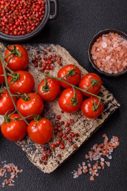 Koyu beton arka planda tuzlu ve baharatlı olgun kırmızı kiraz domatesleri.