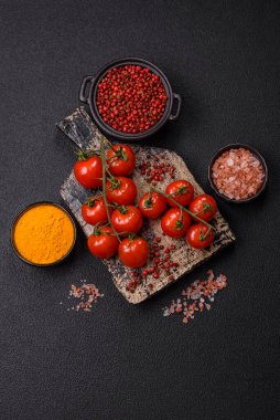 Koyu beton arka planda tuzlu ve baharatlı olgun kırmızı kiraz domatesleri.