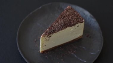 Koyu beton arka planda doğranmış çikolata serpiştirilmiş tatlı cheesecake.