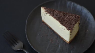 Koyu beton arka planda doğranmış çikolata serpiştirilmiş tatlı cheesecake.