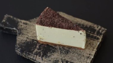 Koyu beton arka planda doğranmış çikolata serpiştirilmiş tatlı cheesecake.