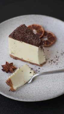 Koyu beton arka planda doğranmış çikolata serpiştirilmiş tatlı cheesecake.