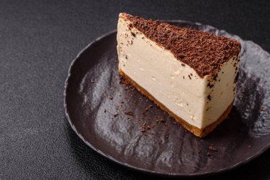 Koyu beton arka planda doğranmış çikolata serpiştirilmiş tatlı cheesecake.