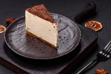 Koyu beton arka planda doğranmış çikolata serpiştirilmiş tatlı cheesecake.