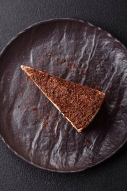 Koyu beton arka planda doğranmış çikolata serpiştirilmiş tatlı cheesecake.