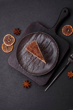 Koyu beton arka planda doğranmış çikolata serpiştirilmiş tatlı cheesecake.