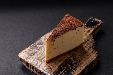 Koyu beton arka planda doğranmış çikolata serpiştirilmiş tatlı cheesecake.