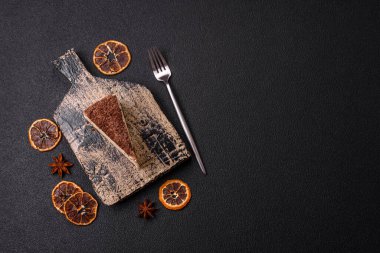 Koyu beton arka planda doğranmış çikolata serpiştirilmiş tatlı cheesecake.