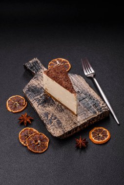 Koyu beton arka planda doğranmış çikolata serpiştirilmiş tatlı cheesecake.