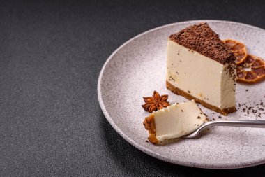 Koyu beton arka planda doğranmış çikolata serpiştirilmiş tatlı cheesecake.