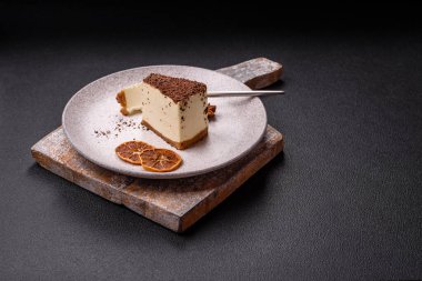 Koyu beton arka planda doğranmış çikolata serpiştirilmiş tatlı cheesecake.