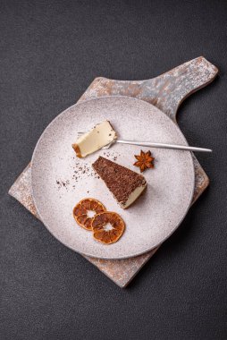 Koyu beton arka planda doğranmış çikolata serpiştirilmiş tatlı cheesecake.