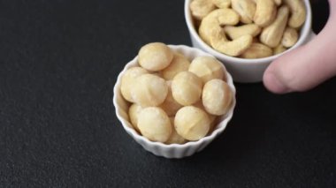 Koyu beton arka planda seramik kasede lezzetli, besleyici Macadamia fındıkları.