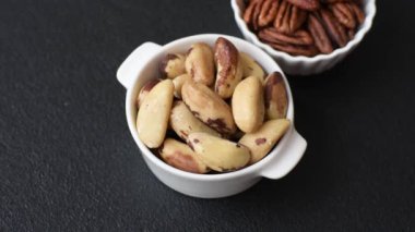 Koyu beton arka planda seramik kasede lezzetli besleyici Brezilya fındıkları.