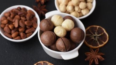 Koyu beton arka planda seramik kasede lezzetli, besleyici Macadamia fındıkları.