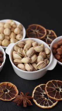 Koyu beton arka planda seramik kasede lezzetli, besleyici fıstıklar.