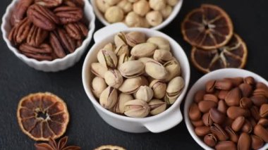 Koyu beton arka planda seramik kasede lezzetli, besleyici fıstıklar.