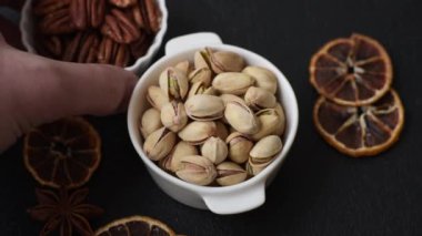 Koyu beton arka planda seramik kasede lezzetli, besleyici fıstıklar.