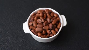 Koyu beton arka planda seramik kasede lezzetli, besleyici sedir fıstıkları.