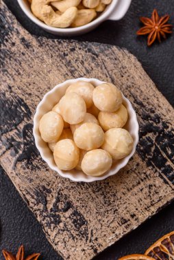 Koyu beton arka planda seramik kasede lezzetli, besleyici Macadamia fındıkları.