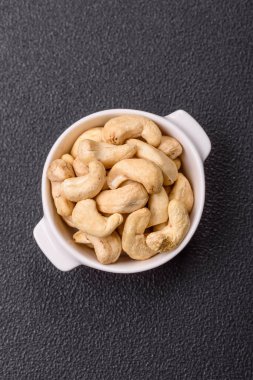 Koyu beton arka planda seramik kasede lezzetli, besleyici fındıklar.