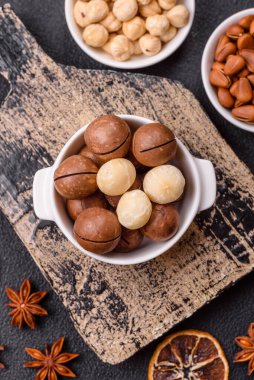 Koyu beton arka planda seramik kasede lezzetli, besleyici Macadamia fındıkları.