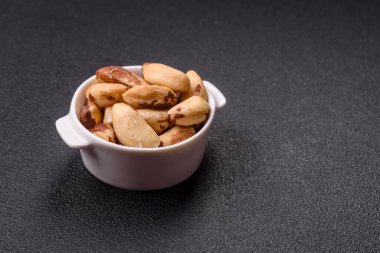 Koyu beton arka planda seramik kasede lezzetli besleyici Brezilya fındıkları.