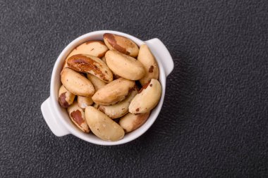 Koyu beton arka planda seramik kasede lezzetli besleyici Brezilya fındıkları.