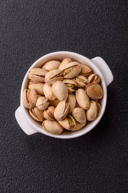 Koyu beton arka planda seramik kasede lezzetli, besleyici fıstıklar.