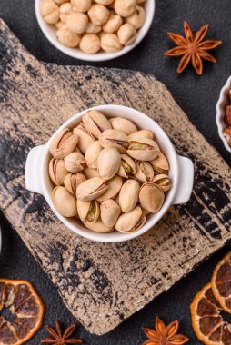 Koyu beton arka planda seramik kasede lezzetli, besleyici fıstıklar.