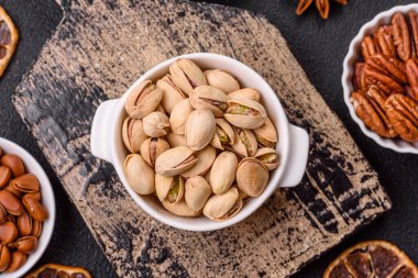 Koyu beton arka planda seramik kasede lezzetli, besleyici fıstıklar.