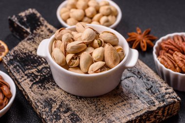 Koyu beton arka planda seramik kasede lezzetli, besleyici fıstıklar.