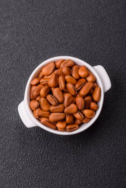 Koyu beton arka planda seramik kasede lezzetli, besleyici sedir fıstıkları.