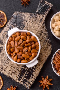 Koyu beton arka planda seramik kasede lezzetli, besleyici sedir fıstıkları.