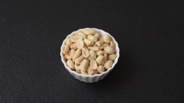 Koyu beton arka planda seramik kasede lezzetli besleyici fıstık.